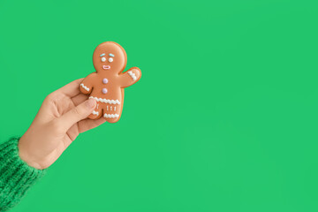 Woman holding Christmas cookie on color background