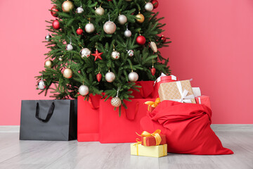 Santa bag with gifts and beautiful Christmas tree near color wall in room