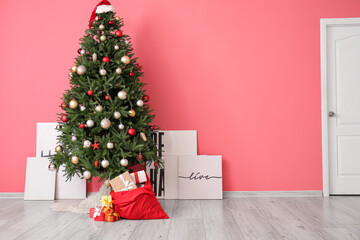 Santa bag with gifts and beautiful Christmas tree near color wall in room