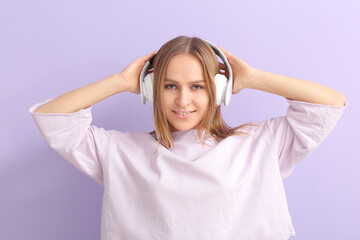 Naklejka premium Beautiful young woman listening to music on color background