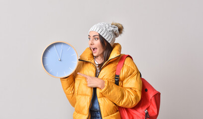 Female student with clock on grey background