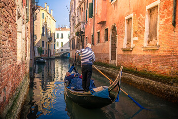 Fototapeta na wymiar Venetian gondolier rowing gondola through the canal