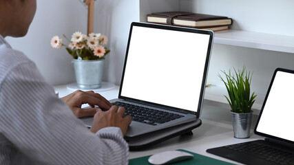Side view of young male  working with multiple electronic devices. Blank screen for advertising text.