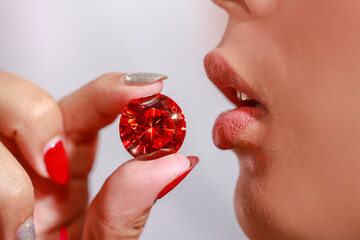 .A lady Use your fingers to hold the red ruby diamond close to her lip