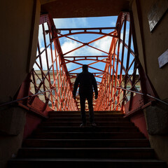 Fototapeta na wymiar Silueta de hombre subiendo las escaleras del puente Eiffel de hierro rojo en Girona , Cataluña, España