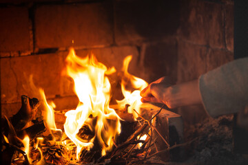 Mano echando leña a la chimenea