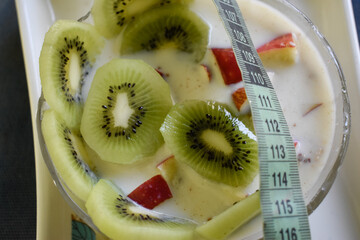 Kiwi and apple oatmeal with measuring tape indicating healthy lifestyle and weight management concept
 - Powered by Adobe