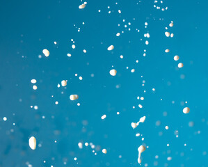 Splashes of white milk isolated on a blue background.