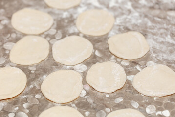 Modeling dumplings from dough on the table.