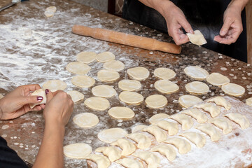 A girl and a woman make dumplings from dough.