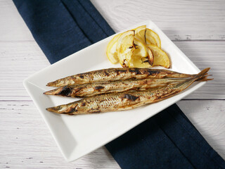 Grilled sand lance and lemon on a white plate
