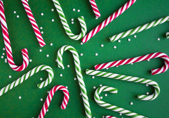 Christmas background with candy canes. Red and green sweet sticks with small stars. Flat lay, overhead view. Poster, banner, greeting card template. Festive backdrop. Holiday season
