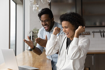 Overjoyed African American man and woman feel euphoric winning online lottery on laptop. Happy...