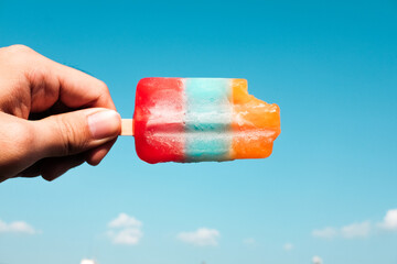 Hand holding popsicle to the blue sky