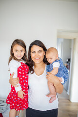 Happy woman hugging her adorable young daughters