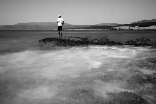Urla, Izmir, Turkey; A child is fishing on the Altınköy cliffs, there is a flurry of movement due to the long exposure. 11 July 2020