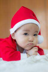 Christmas and New Year funny happy curious Asian infant baby in Santa Claus clothes