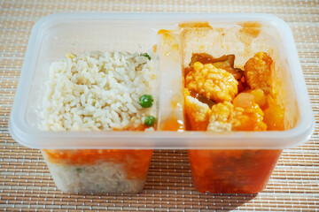 Sweet and sour chicken and jasmine rice in a plastic container. Asian take away and ready meals concept.