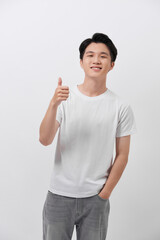 Smiling young handsome casual Asian man giving thumbs up studio shot isolated on white background