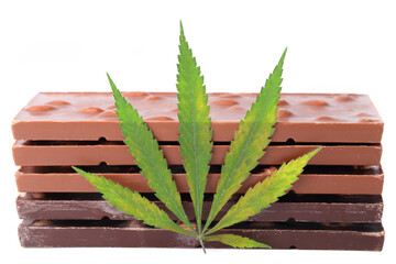 Two bars of black and three milk chocolate and a green hemp leaf on a white isolated background....