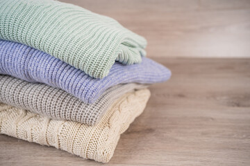 Obraz na płótnie Canvas a stack of warm cozy woolen sweaters jersey jumpers for the winter