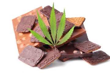 Bars of black and milk chocolate with cookies containing CBD cannabis and green hemp leaf on white isolated background. Chocolate with marijuana extract. Entertainment drug concept