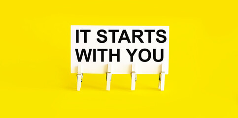 text It Starts With You on white short note paper on yellow background