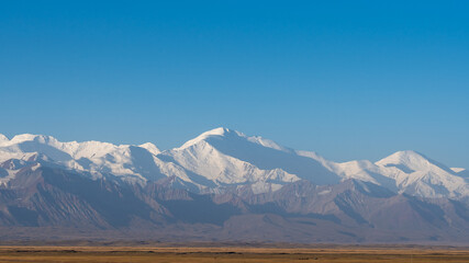 Morning panorama of stunning snow-capped Trans-Alay mountain range with Lenin Peak in south Kyrgyzstan