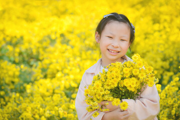 Young beautiful asian girl child holding flower and smiles in yellow Chrysanthemum field.