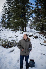 Handsome man holding a drone with snowy pines as background