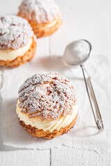 Homemade and tasty cream puffs and strainer with powdered sugar