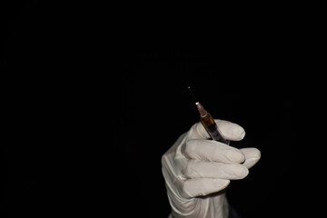 Close-up of hand of medical person with vaccine syringe isolated on black