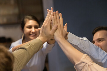 Crop close up of excited multiracial colleagues give high five celebrate shared business success...