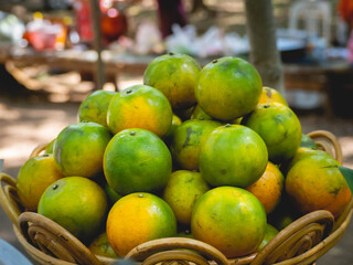 A pile of oranges green-yellow inside the wooden basket