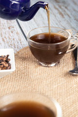 Serving tea from a teapot - Cup of black tea on white woods - tea infusion - tea time