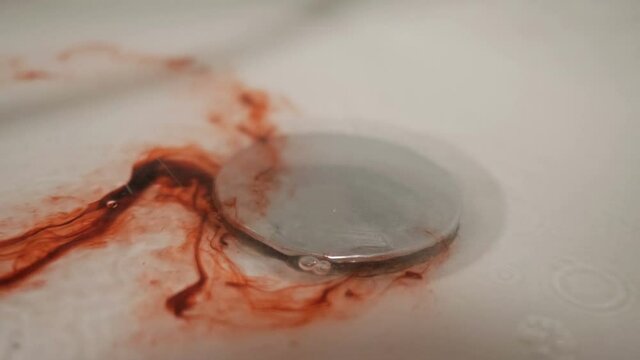Blood with water flows down the drain hole in the shower. Metaphor.