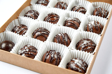 Round dark chocolate candies in a white box close up