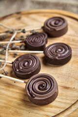 Round milk chocolate sweets on a stick, on a wooden tray