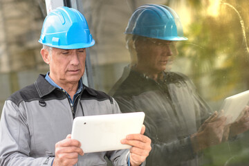 Portrait of a male  craftman reading his notes on a tablet on a construction site