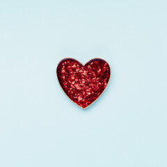 Valentines Day concept. Blue empty frame and red glitter heart on pastel blue background. Flat lay, top view, copy space.