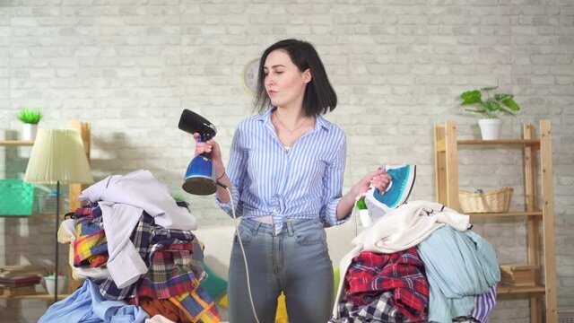 Young housewife chooses between an iron and a steamer for Ironing clothes