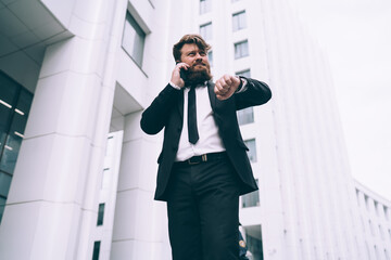 Businessman calling on smartphone and checking time