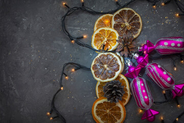 Christmas garland, candies and dried orange slices on gray concrete background. Christmas composition, New Years night. Top view, selective focus, fog view