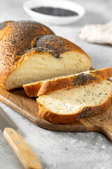Homemade crusty loave of wheat candy bun with poppy seed on wooden background. Still life, dark mood, banner layout. Traditional techniques bakery concept	