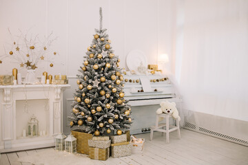 Big beautiful Christmas tree with gifts in a white decorated hall for the New Year. Piano. White teddy bear
