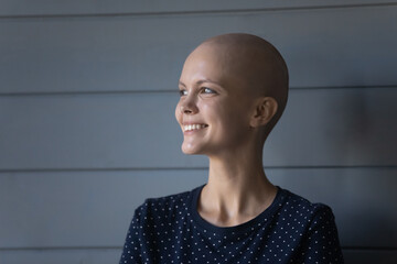 Head shot close up smiling dreamy hairless sick woman looking to aside, young female cancer patient...