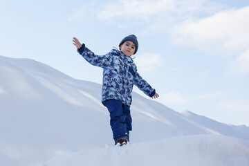 little boy in winter clothes standing in white snow