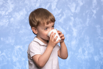 little boy drinks water from a disposable cup of cornstarch. ecologicaly clean. replacing plastic...