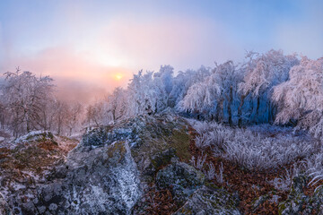 Panorama the setting sun shines through the fog and clouds in the mountains in freezing weather