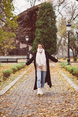 Outdoor portrait of woman in park wearing winter black coat and white scarf.
 